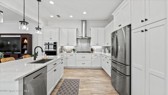 kitchen with stainless steel appliances, a sink, visible vents, ornamental molding, and wall chimney range hood