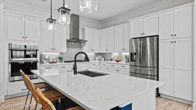 kitchen featuring wall chimney exhaust hood, ornamental molding, a sink, and stainless steel appliances