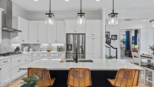 kitchen with crown molding, wall chimney exhaust hood, backsplash, and stainless steel appliances