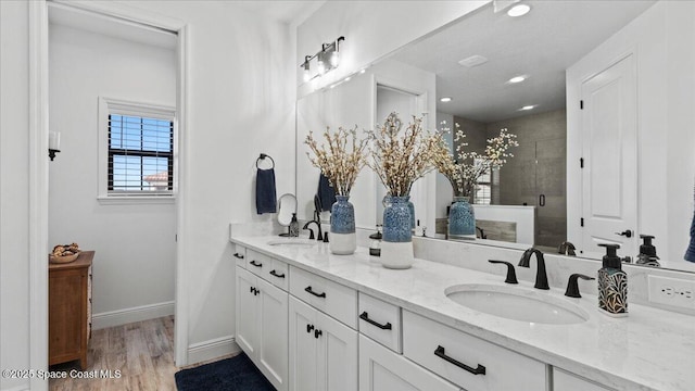 full bathroom featuring a shower stall, baseboards, a sink, and wood finished floors