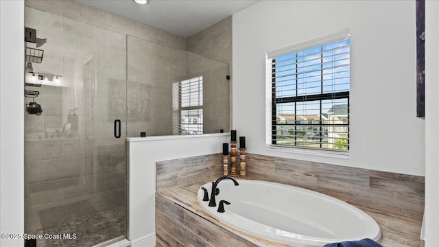 full bathroom with a shower stall and a bath