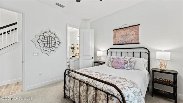 bedroom with ceiling fan, connected bathroom, and light carpet