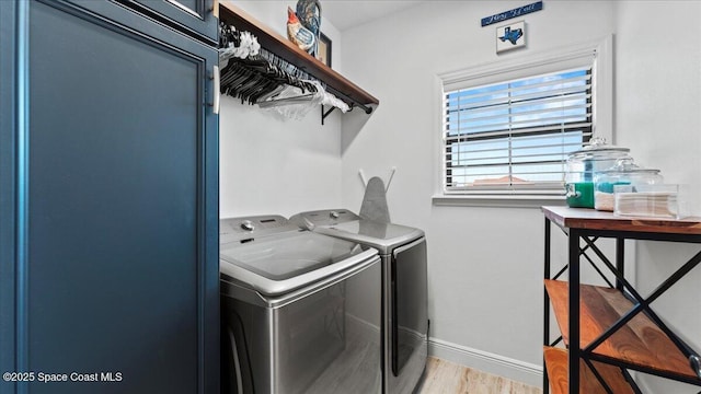 clothes washing area featuring laundry area, washing machine and dryer, baseboards, and light wood finished floors