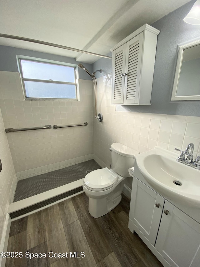 bathroom with hardwood / wood-style flooring, backsplash, tiled shower, vanity, and toilet