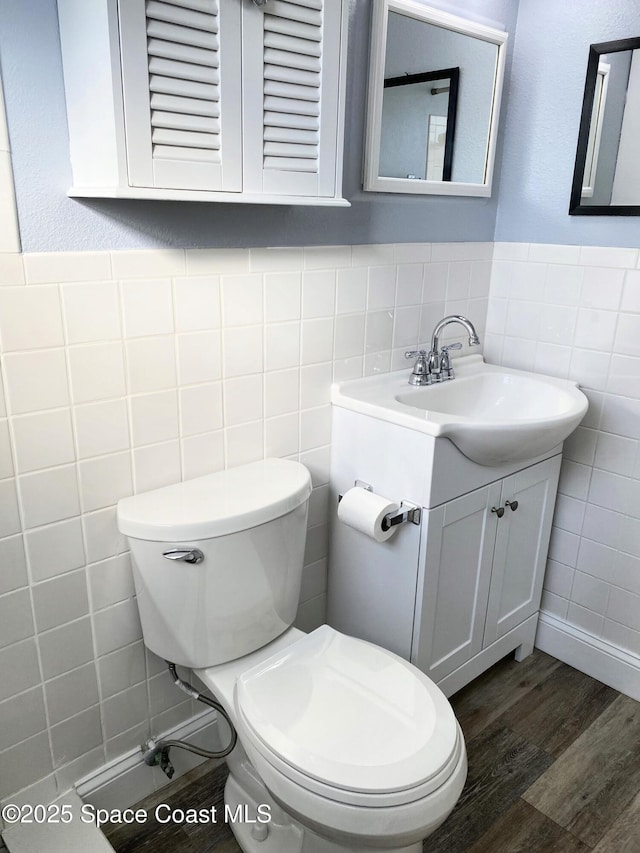 bathroom featuring vanity, hardwood / wood-style floors, tile walls, and toilet