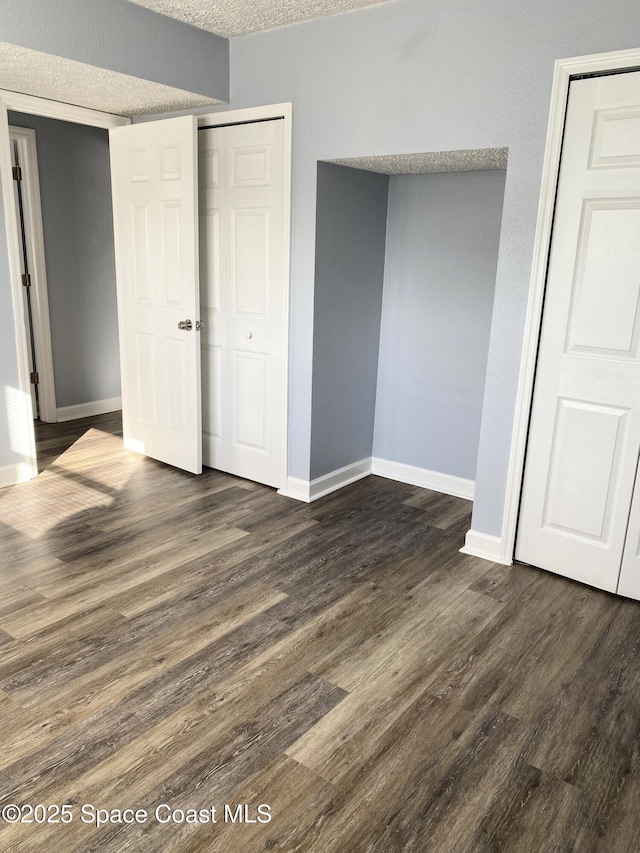 unfurnished bedroom featuring dark wood-type flooring, a textured ceiling, and a closet