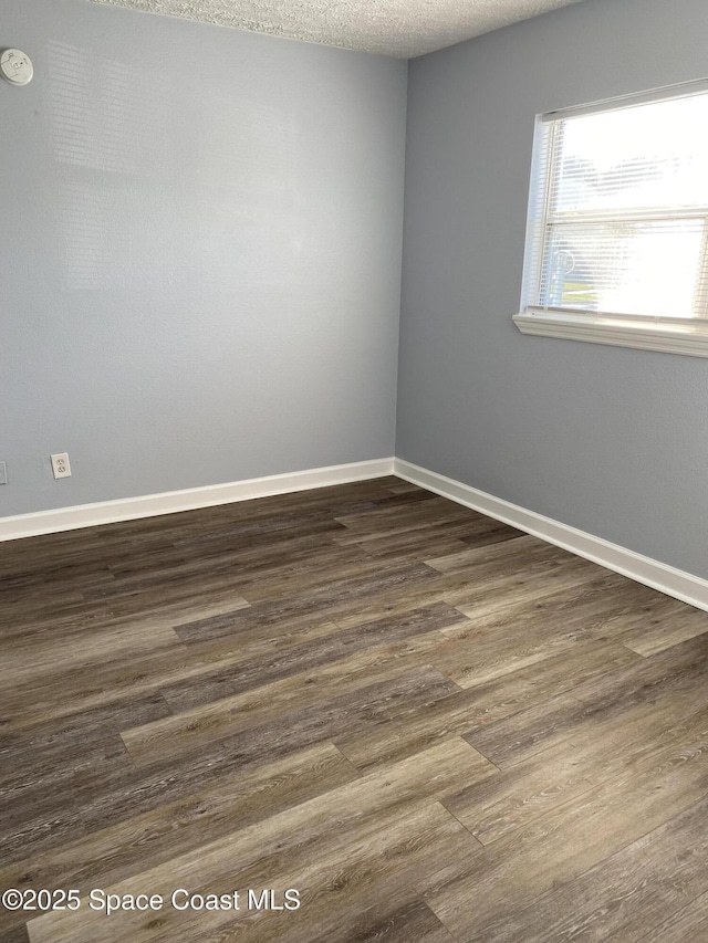 spare room with dark wood-type flooring and a textured ceiling