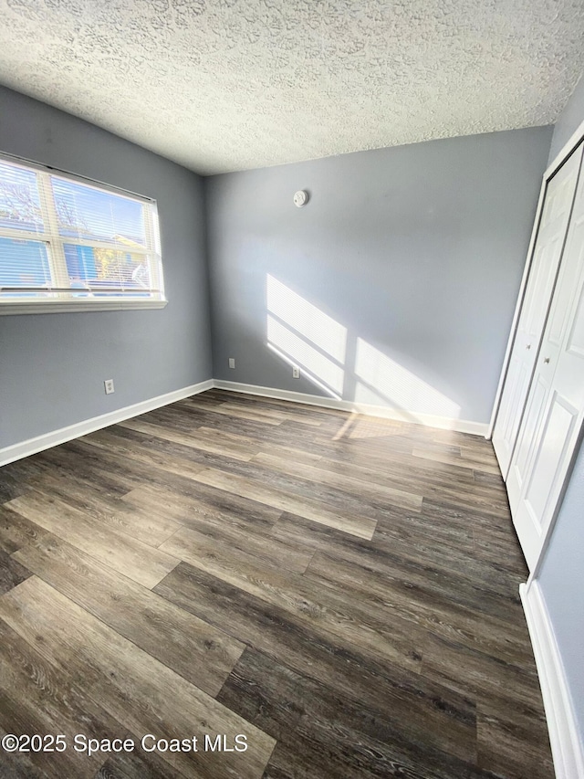 empty room featuring dark hardwood / wood-style flooring and a textured ceiling