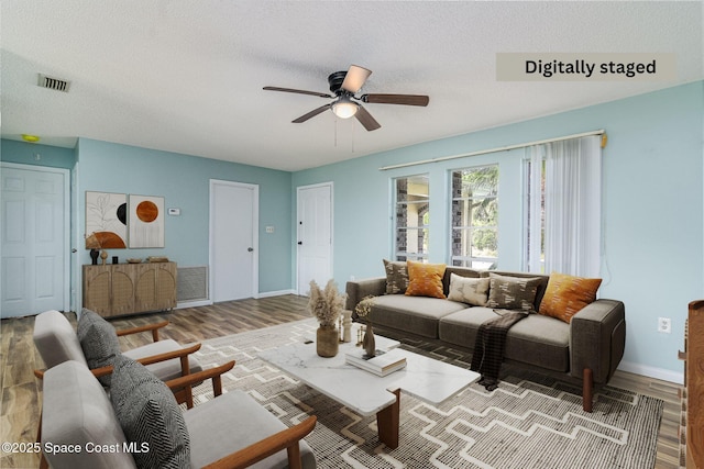 living room with ceiling fan, wood-type flooring, and a textured ceiling