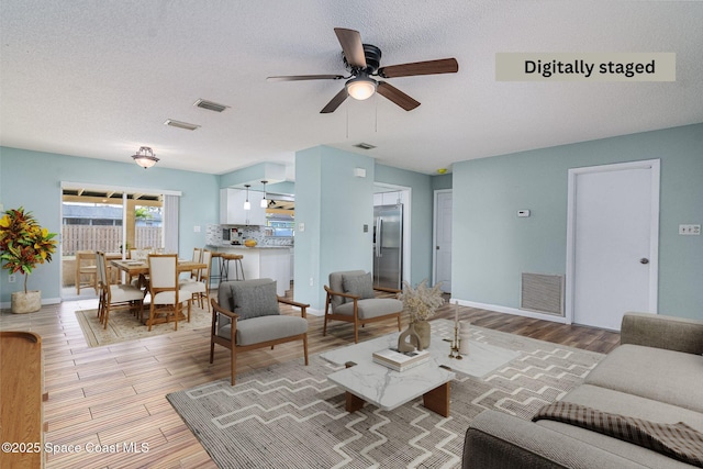 living room featuring ceiling fan and a textured ceiling