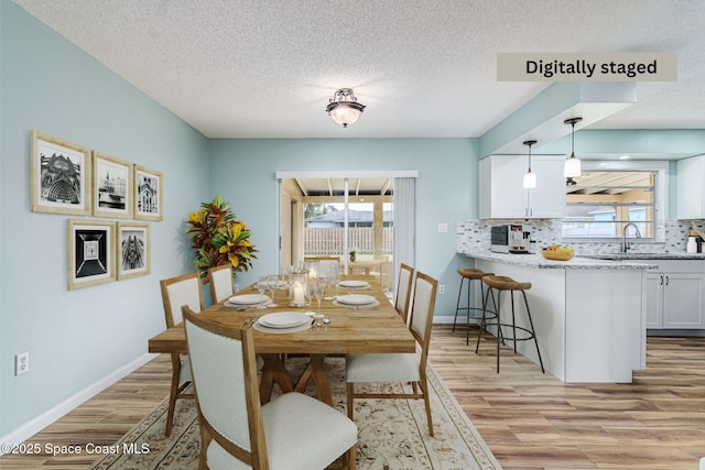 dining room featuring sink, a textured ceiling, and light wood-type flooring