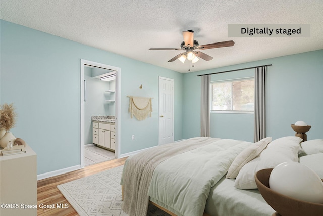 bedroom with ceiling fan, ensuite bathroom, a textured ceiling, and light hardwood / wood-style flooring