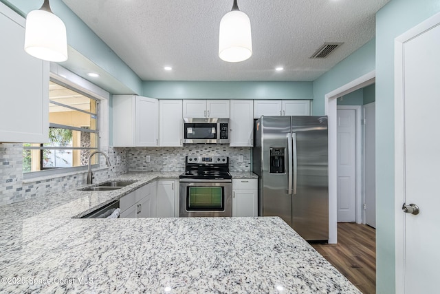 kitchen featuring white cabinetry, hanging light fixtures, stainless steel appliances, and sink