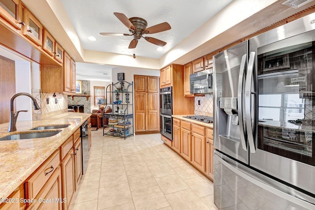 kitchen featuring sink, backsplash, stainless steel appliances, light stone counters, and a raised ceiling