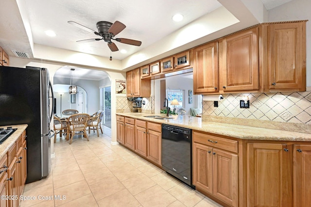 kitchen with sink, stainless steel fridge, black dishwasher, light stone countertops, and a raised ceiling