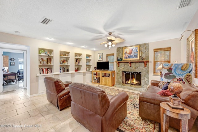 living room featuring built in shelves, a textured ceiling, light tile patterned floors, ceiling fan, and a fireplace