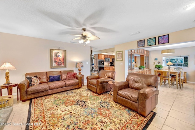 living room with light tile patterned flooring, ceiling fan, and a textured ceiling