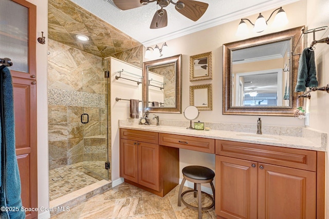 bathroom with ceiling fan, vanity, ornamental molding, a textured ceiling, and a shower with shower door