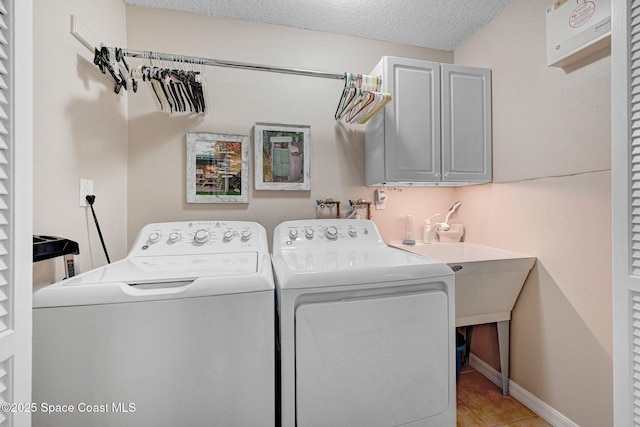 laundry room featuring independent washer and dryer, cabinets, a textured ceiling, and light tile patterned floors