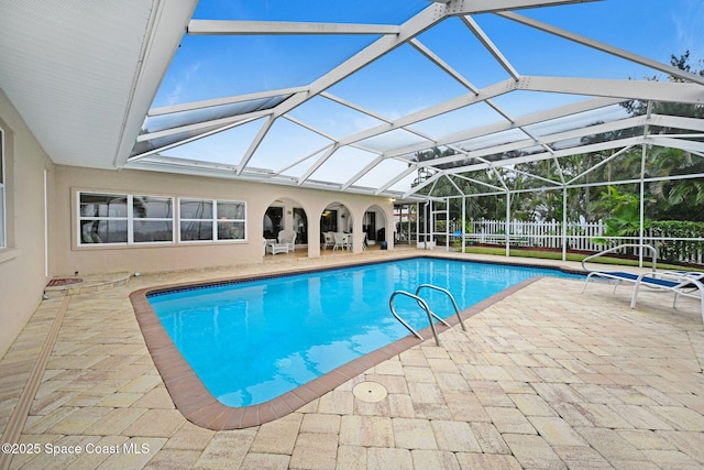 view of swimming pool featuring a patio and glass enclosure