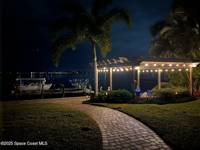 view of community featuring a water view, a pergola, a lawn, and a boat dock