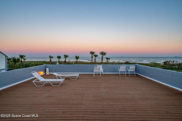 deck at dusk featuring a water view