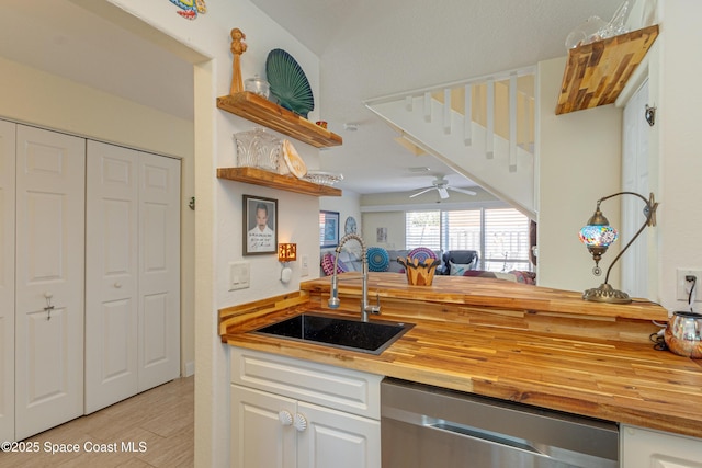 kitchen with white cabinetry, stainless steel dishwasher, butcher block counters, and sink