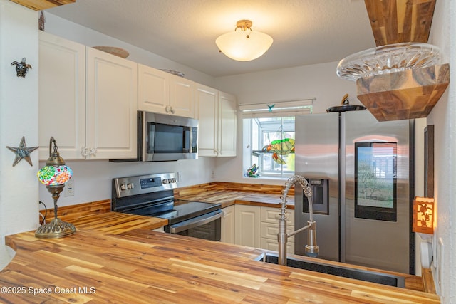 kitchen with butcher block countertops, sink, white cabinets, and appliances with stainless steel finishes