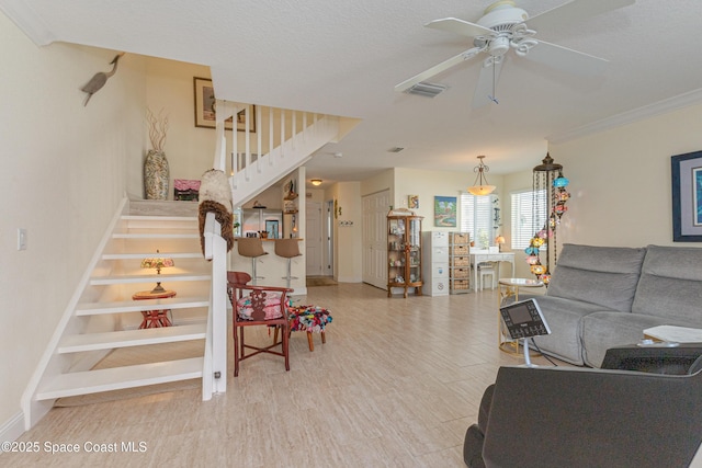 living room with ceiling fan, ornamental molding, and light wood-type flooring