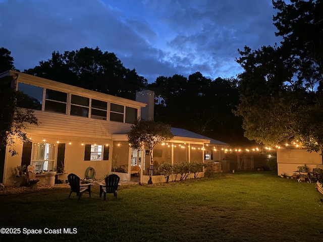 back house at dusk featuring an outdoor fire pit and a yard