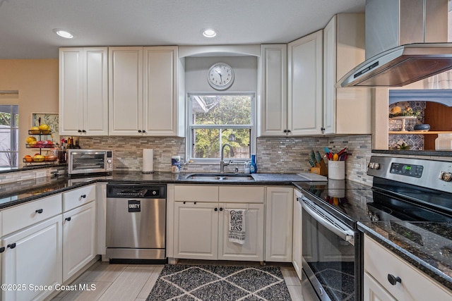 kitchen with a sink, stainless steel appliances, exhaust hood, and white cabinetry