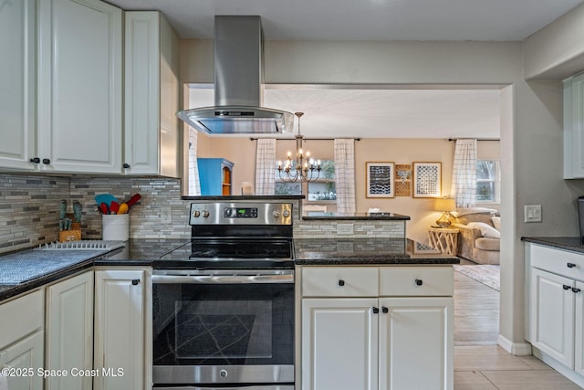 kitchen with white cabinets, stainless steel range with electric cooktop, decorative backsplash, island exhaust hood, and an inviting chandelier