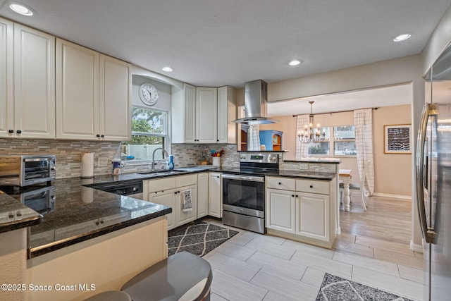 kitchen featuring a peninsula, hanging light fixtures, stainless steel appliances, a sink, and exhaust hood