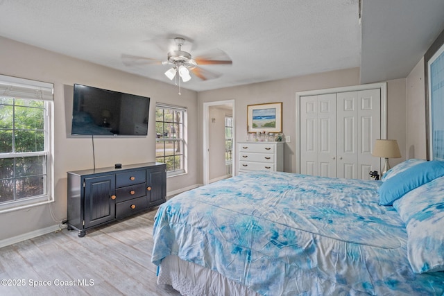 bedroom with baseboards, light wood-style flooring, a ceiling fan, and a textured ceiling