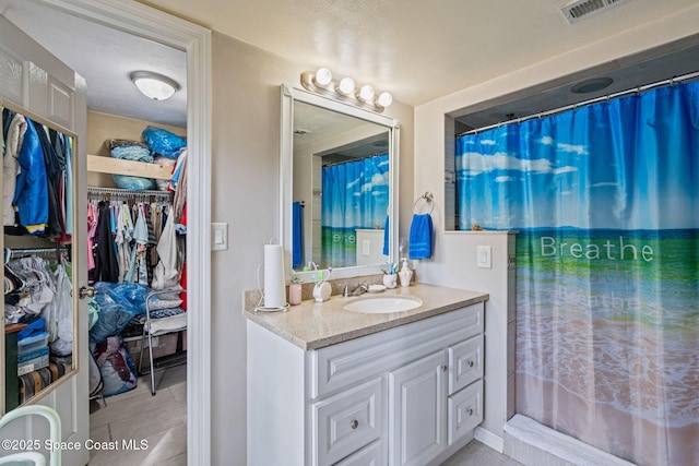 full bathroom with visible vents, a spacious closet, curtained shower, and vanity