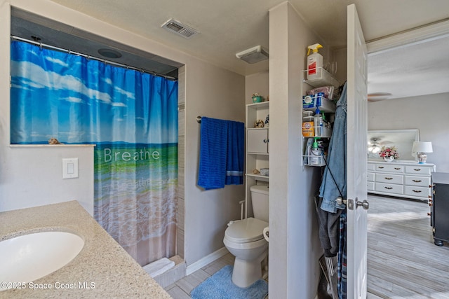 bathroom featuring visible vents, a shower with shower curtain, toilet, vanity, and wood finished floors