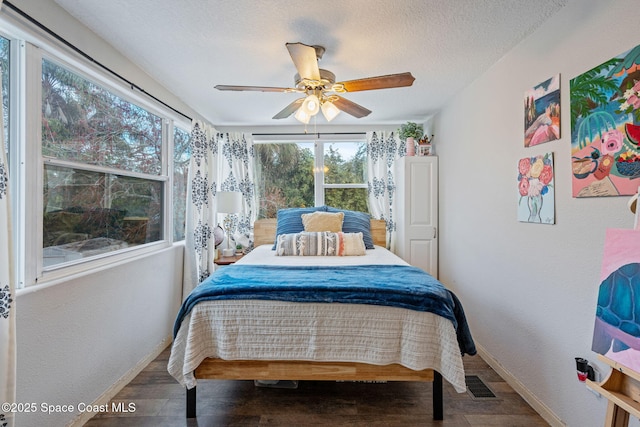 bedroom with a textured ceiling, ceiling fan, wood finished floors, visible vents, and baseboards