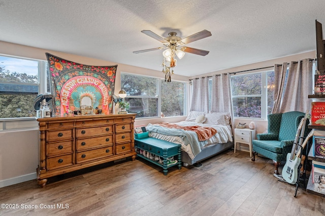 bedroom with baseboards, a textured ceiling, a ceiling fan, and wood finished floors