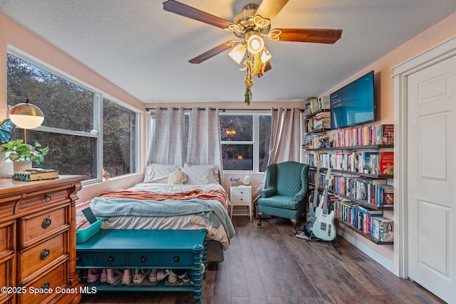 bedroom with a textured ceiling, ceiling fan, and dark wood finished floors