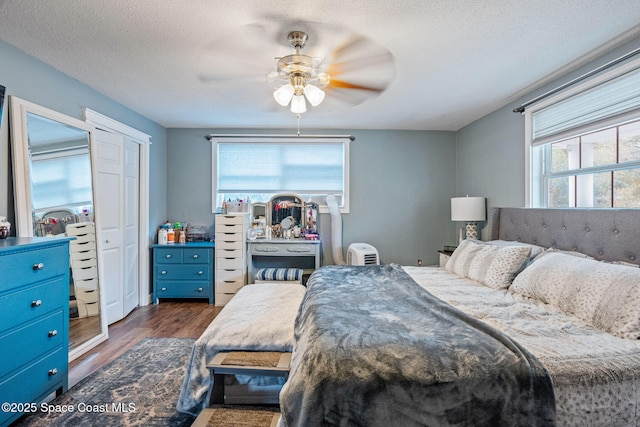 bedroom with dark wood finished floors, a textured ceiling, and ceiling fan