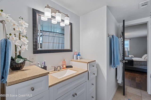 ensuite bathroom with baseboards, visible vents, connected bathroom, tile patterned floors, and vanity