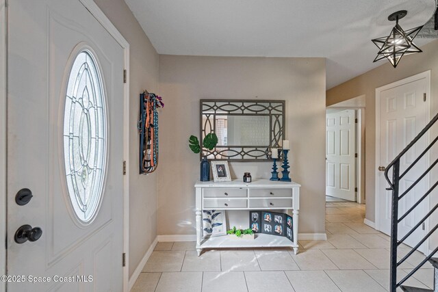 entrance foyer with light tile patterned floors, baseboards, and stairs