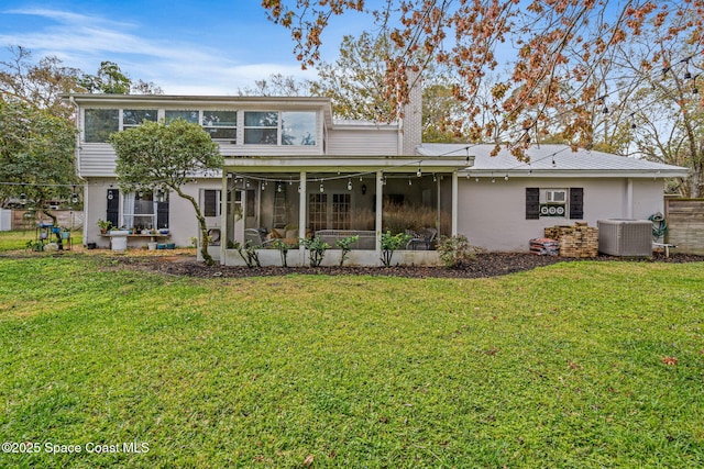 back of house with central AC, a sunroom, a lawn, stucco siding, and a chimney