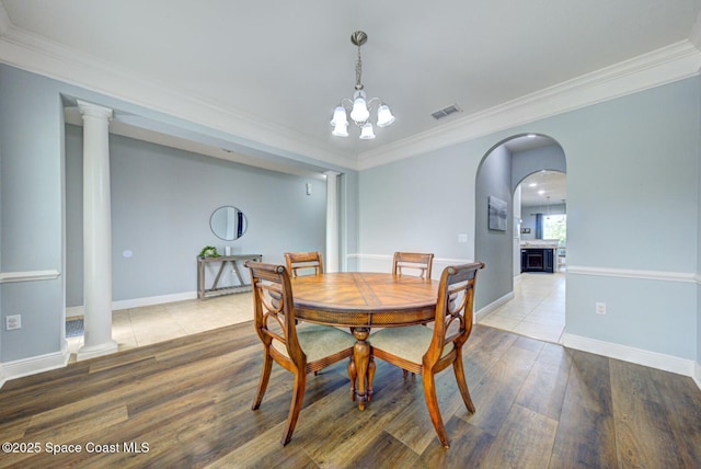 dining area featuring decorative columns, ornamental molding, and wood finished floors