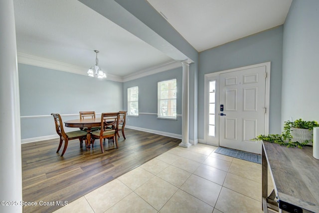 foyer entrance featuring light tile patterned floors, decorative columns, baseboards, and crown molding