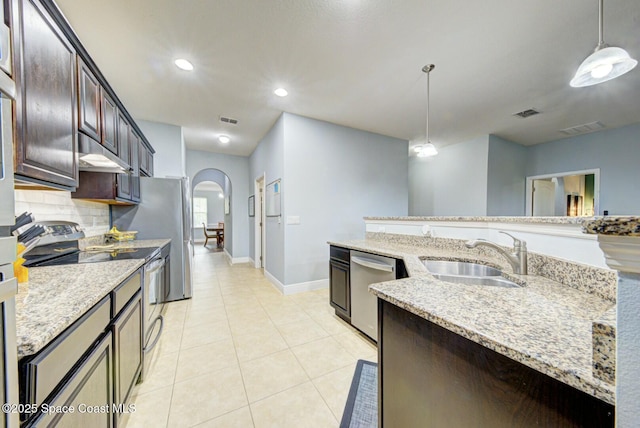 kitchen featuring stainless steel appliances, light stone countertops, sink, and hanging light fixtures