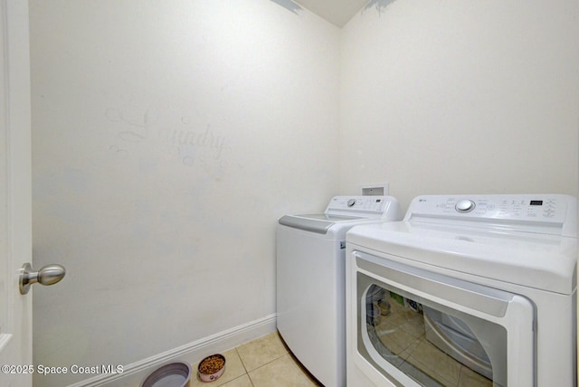 clothes washing area featuring light tile patterned flooring and washer and dryer