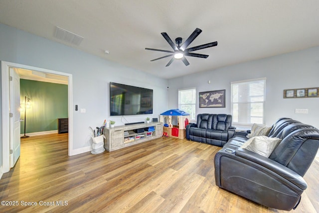 living area with baseboards, visible vents, ceiling fan, and wood finished floors