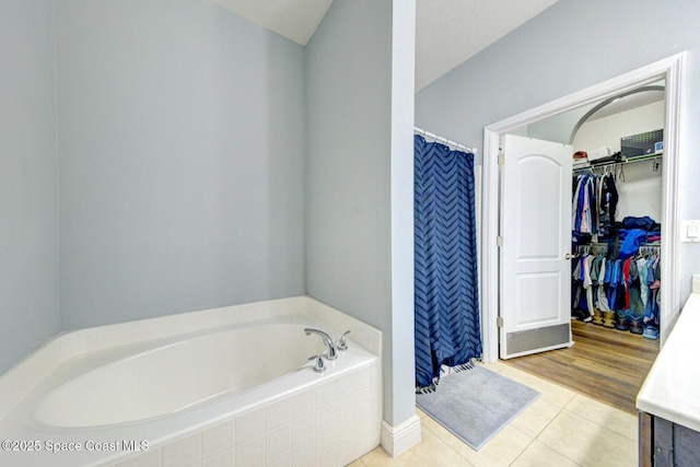 bathroom featuring a stall shower, a spacious closet, a garden tub, and tile patterned floors