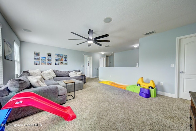 carpeted living area featuring a ceiling fan, baseboards, visible vents, and a textured ceiling